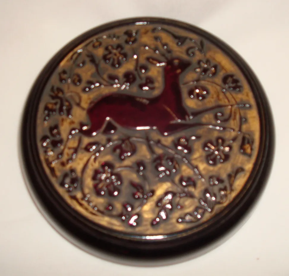 Antique box with embossed deer details surrounded by flowers.