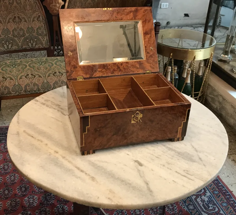 Caja antigua con compartimentos y reflejo en la tapa.