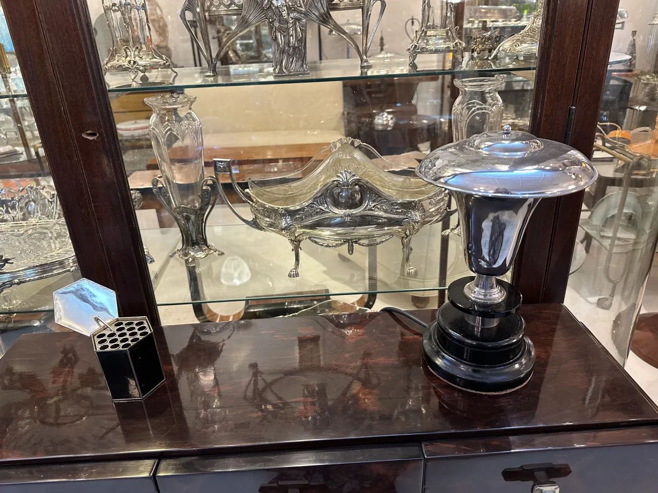 Caja antigua decorativa en un estante lleno de antigüedades.