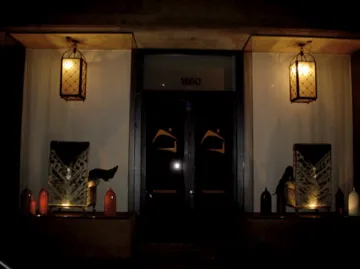 Two antique lanterns illuminate a doorway in a dark setting