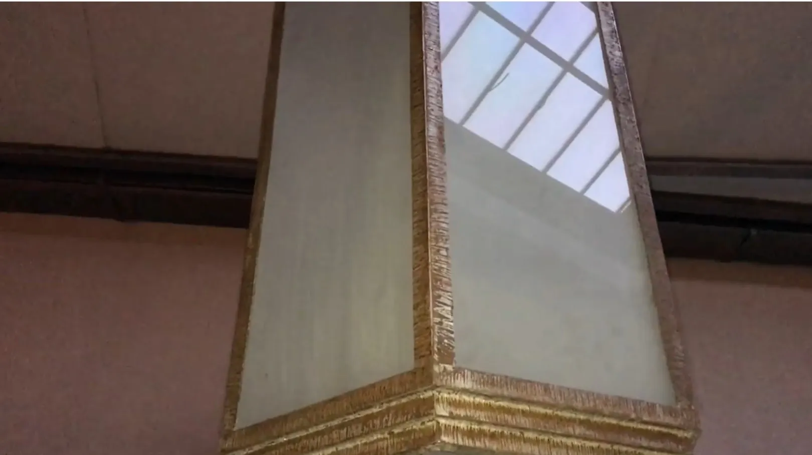 Deux lanternes de plafond anciennes avec un design décoratif, réfléchissant la lumière.