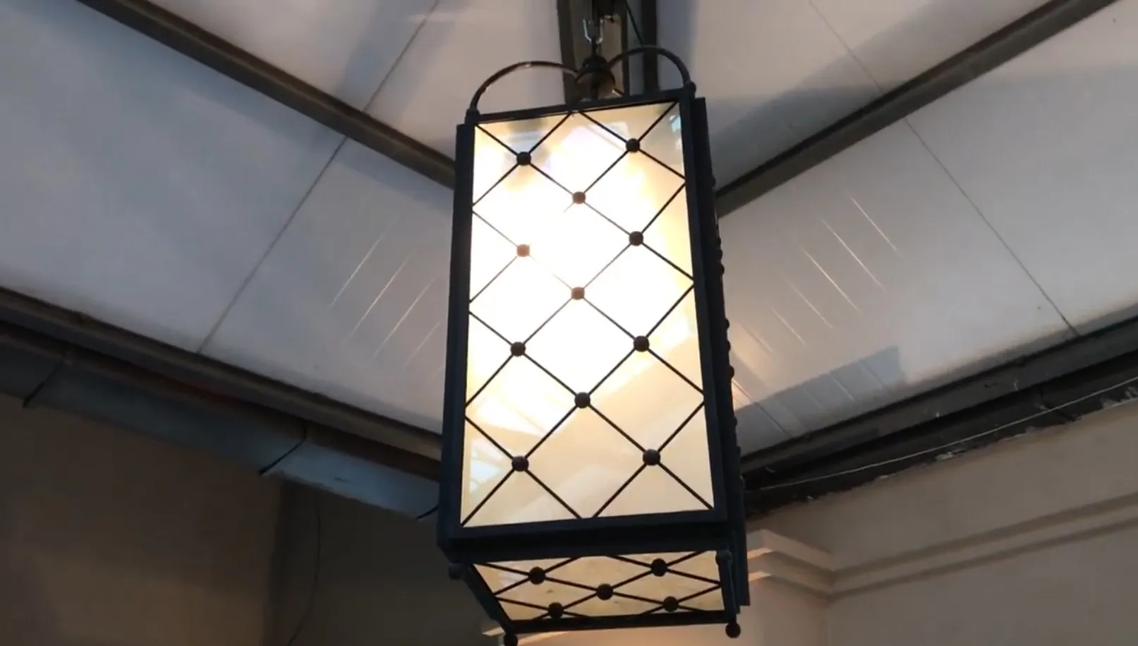 Antique ceiling lantern with black grid design and bright light. Elegant ambiance.
