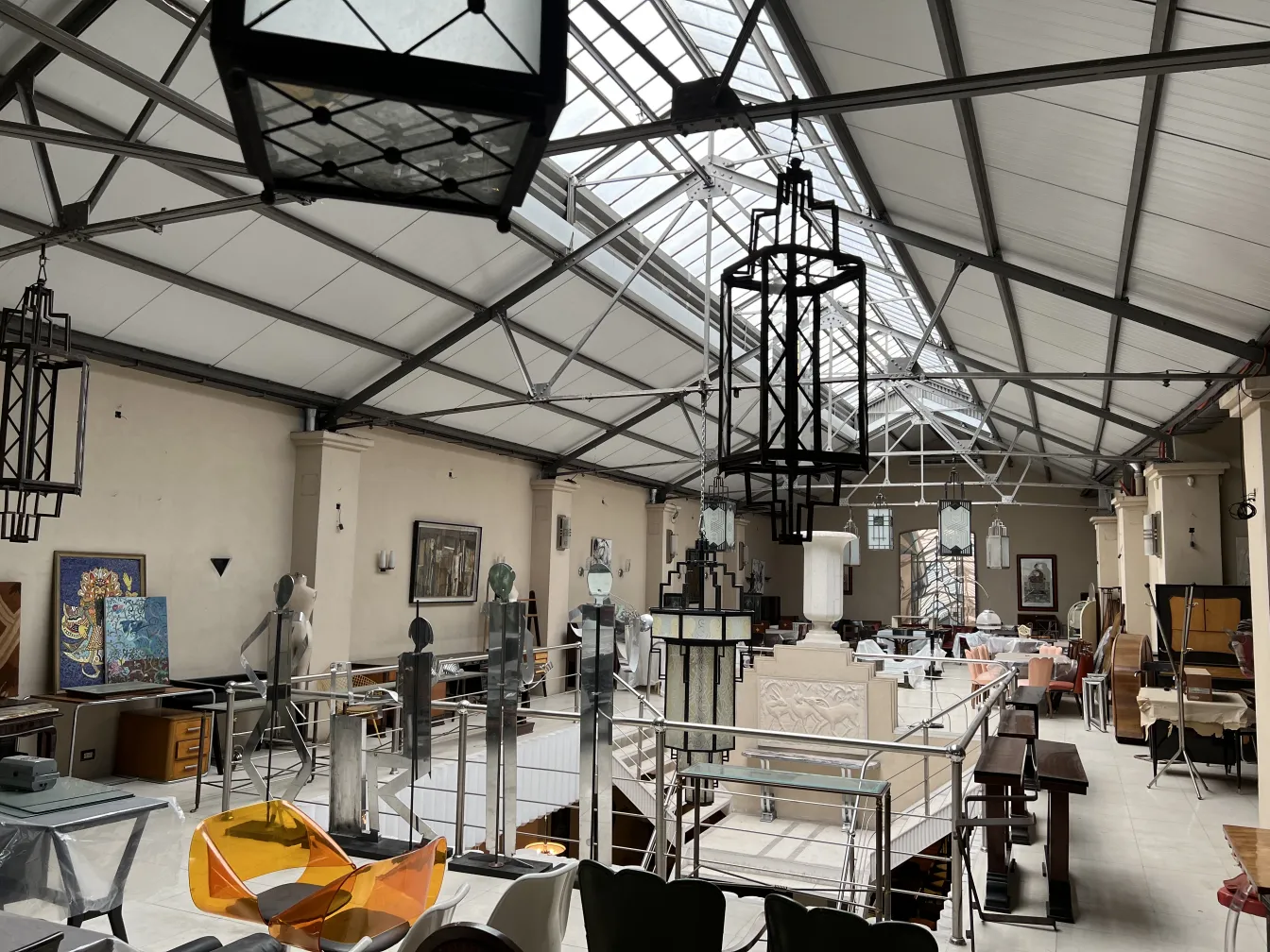 Zwei antike Lampen hängen in einem geräumigen industriellen Umfeld mit mechanischen Details im Hintergrund.