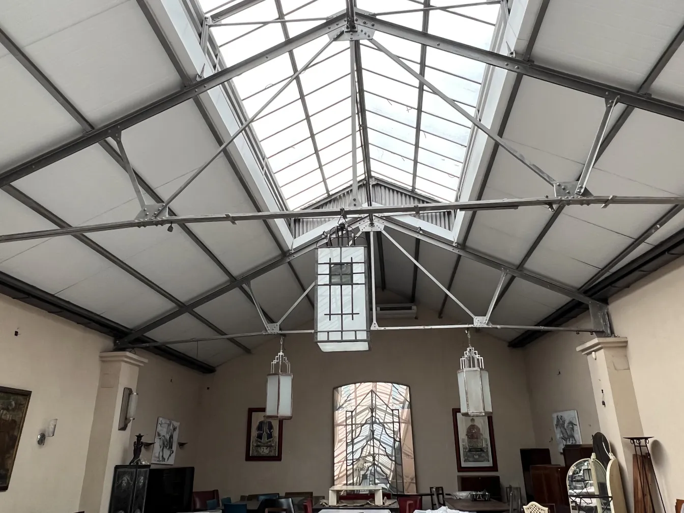 Due lanterne antiche appese in un ampio spazio con soffitto in vetro.