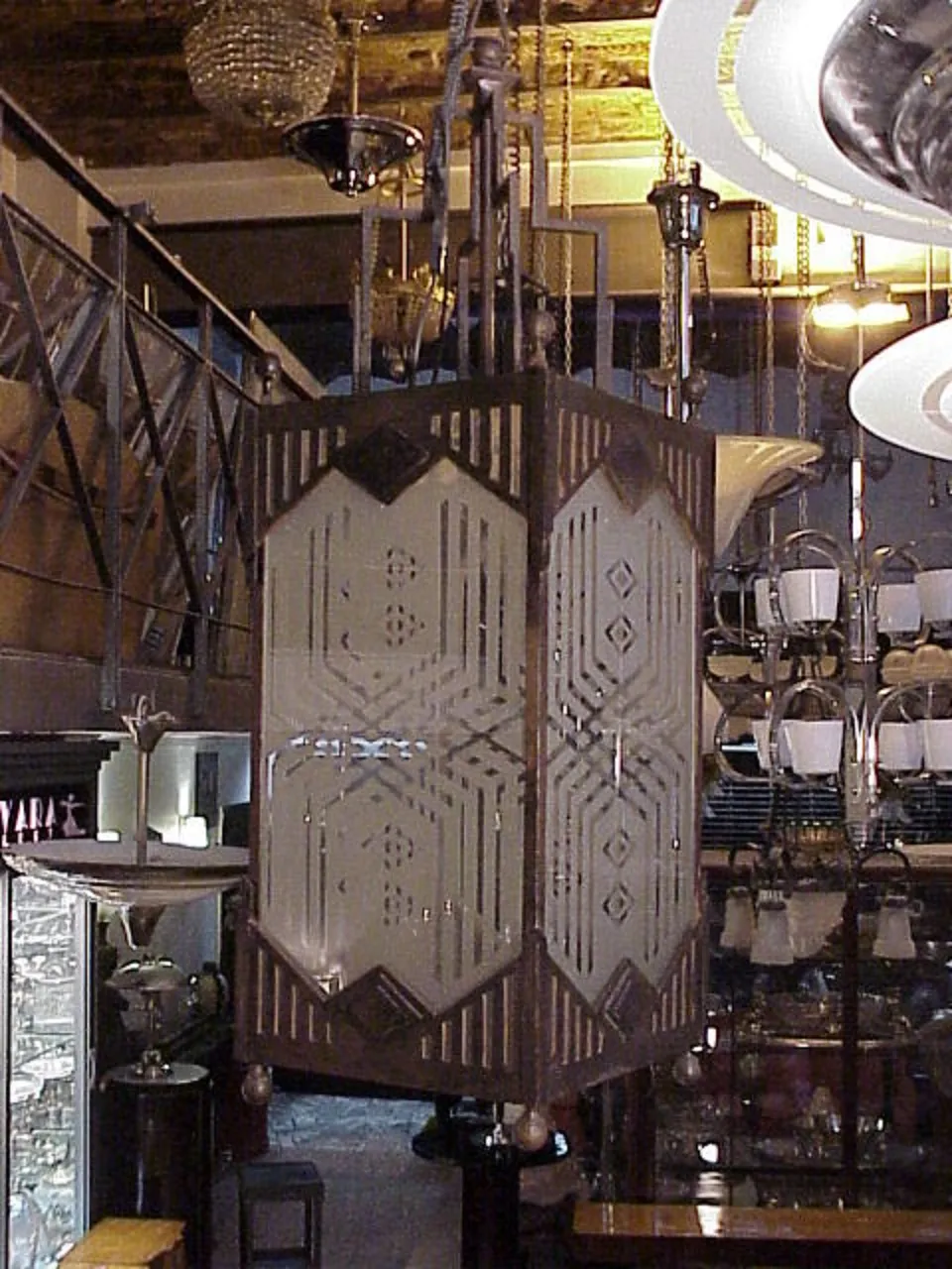 Deux lanternes anciennes suspendues avec des motifs décoratifs, éclairant un environnement accueillant avec d'autres objets autour.