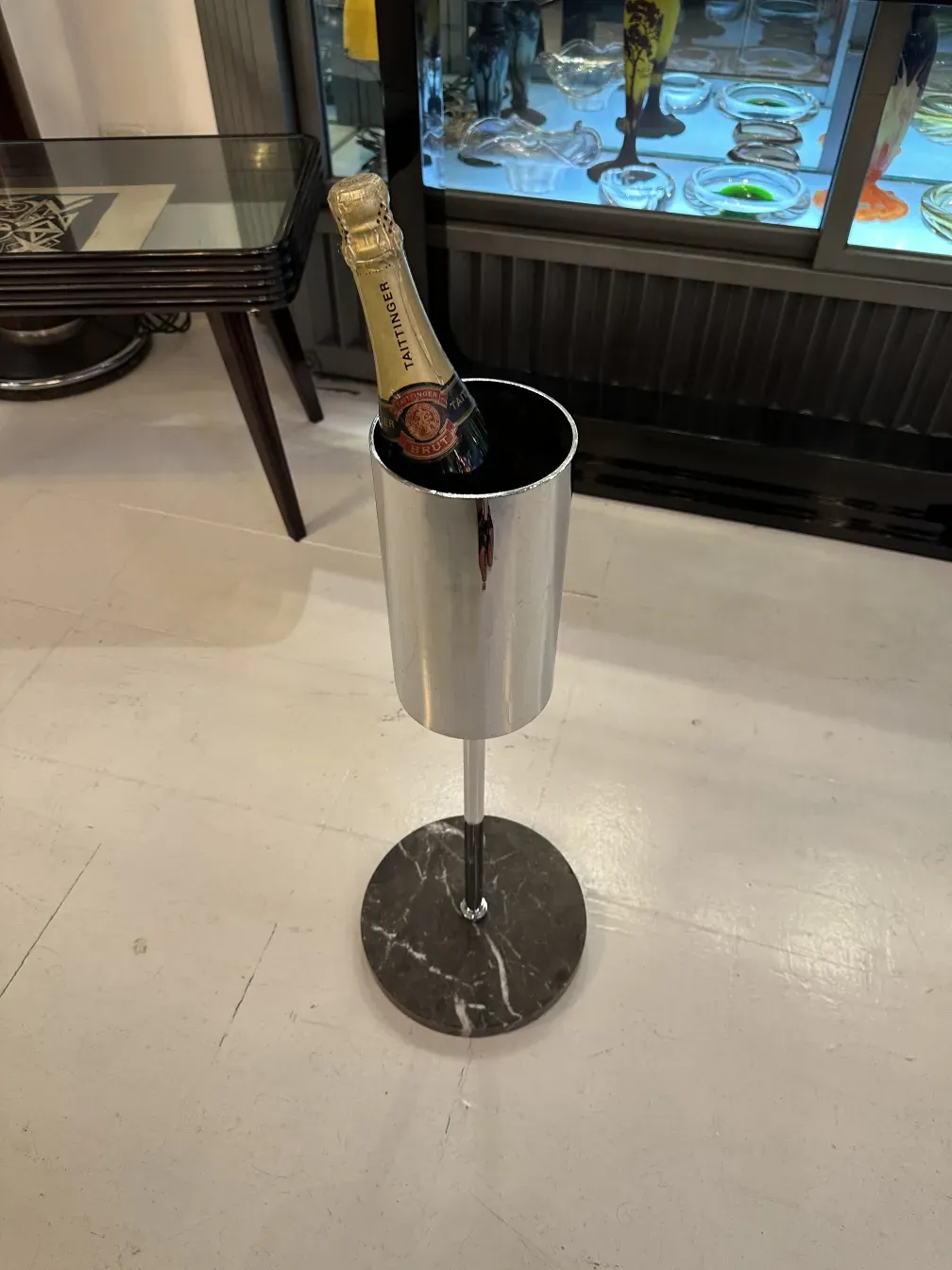 Champagnerflasche in elegantem Kühler mit schwarzem Marmorfuß.