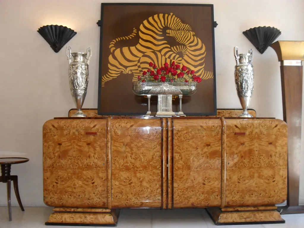 antique sideboard with decorations on top, flanked by silver vases and wall art