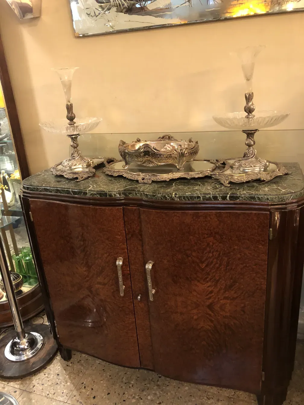 Антикварный буфет с мраморной столешницей и серебряными украшениями, украшенный стеклянными предметами.
