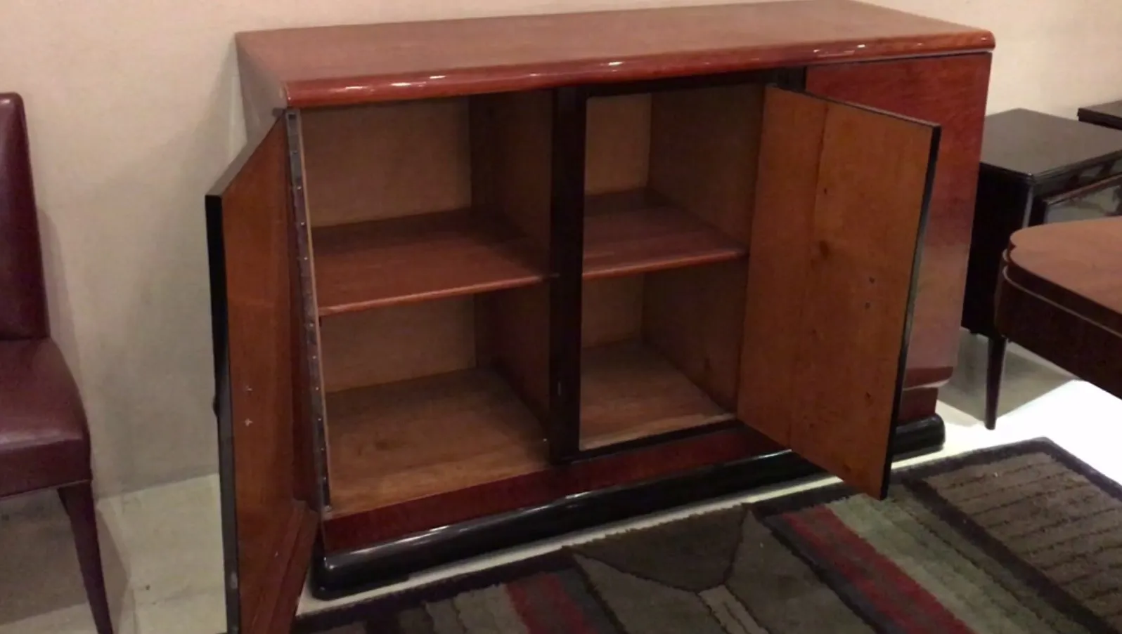 Vaisselier ancien ouvert avec espace de rangement visible, entouré d'une atmosphère chaleureuse et conviviale.