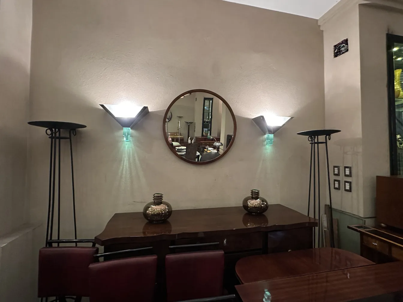 Antike Anrichte mit dekorativem Spiegel und modernen Lampen, warmes Ambiente.