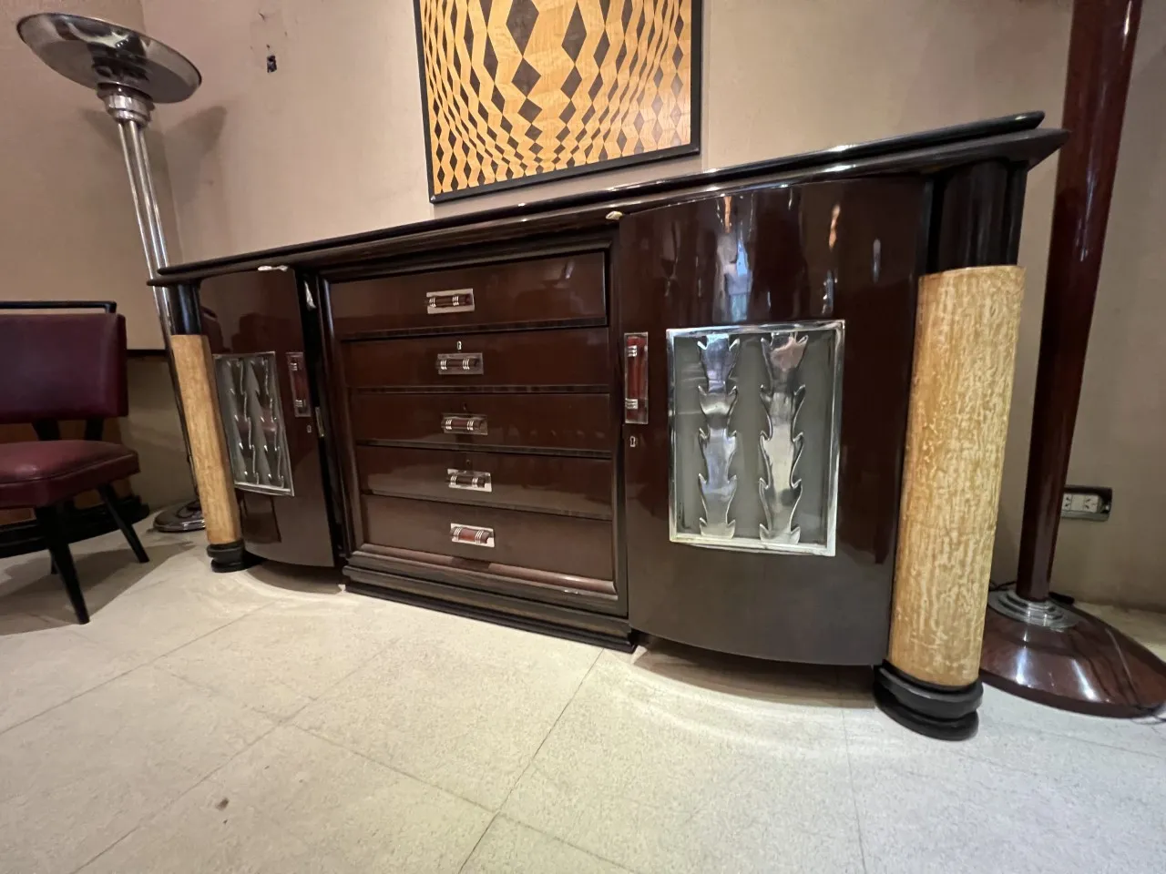 aparador antiguo de madera oscuro con diseño distintivo y detalles en plata, en un ambiente acogedor.