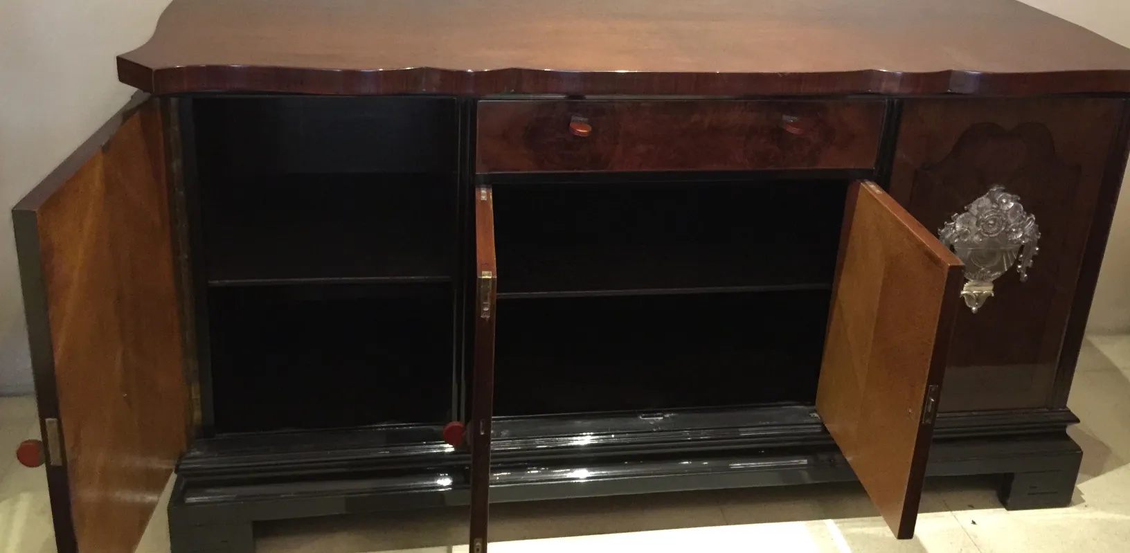 Credenza antica con porte aperte e dettagli decorativi.