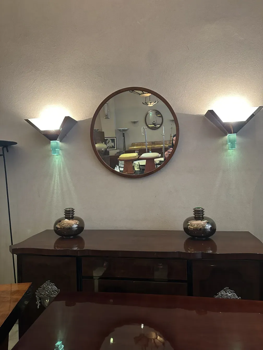 Antique sideboard with round mirror, modern setting. Lamps on the sides