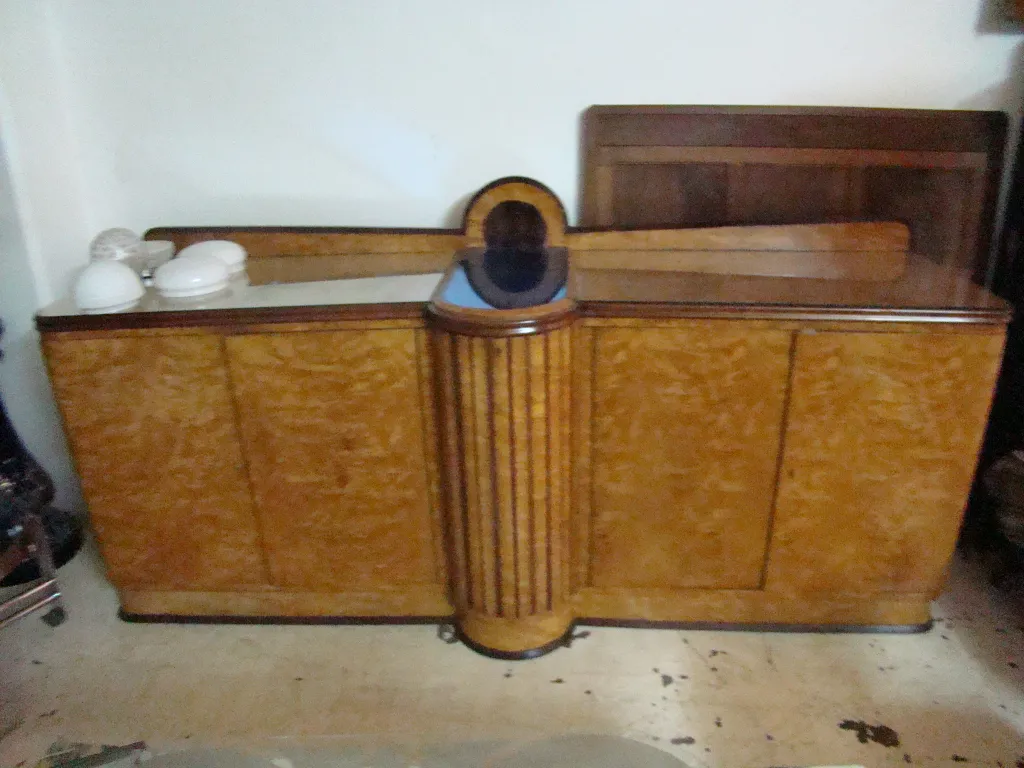 Aparador antiguo con diseño curvado y detalles sobrios, decorado con vajilla blanca.