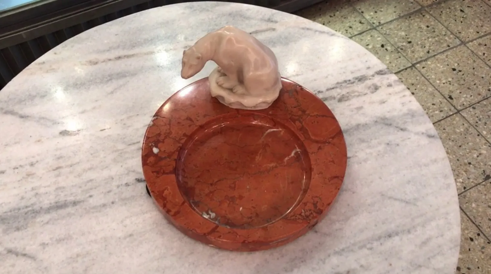 Ceramic standing ashtray shaped like a bear, on a marble table.