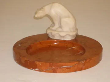 Cinzeiro de pé antigo com figura decorativa, fundo neutro.