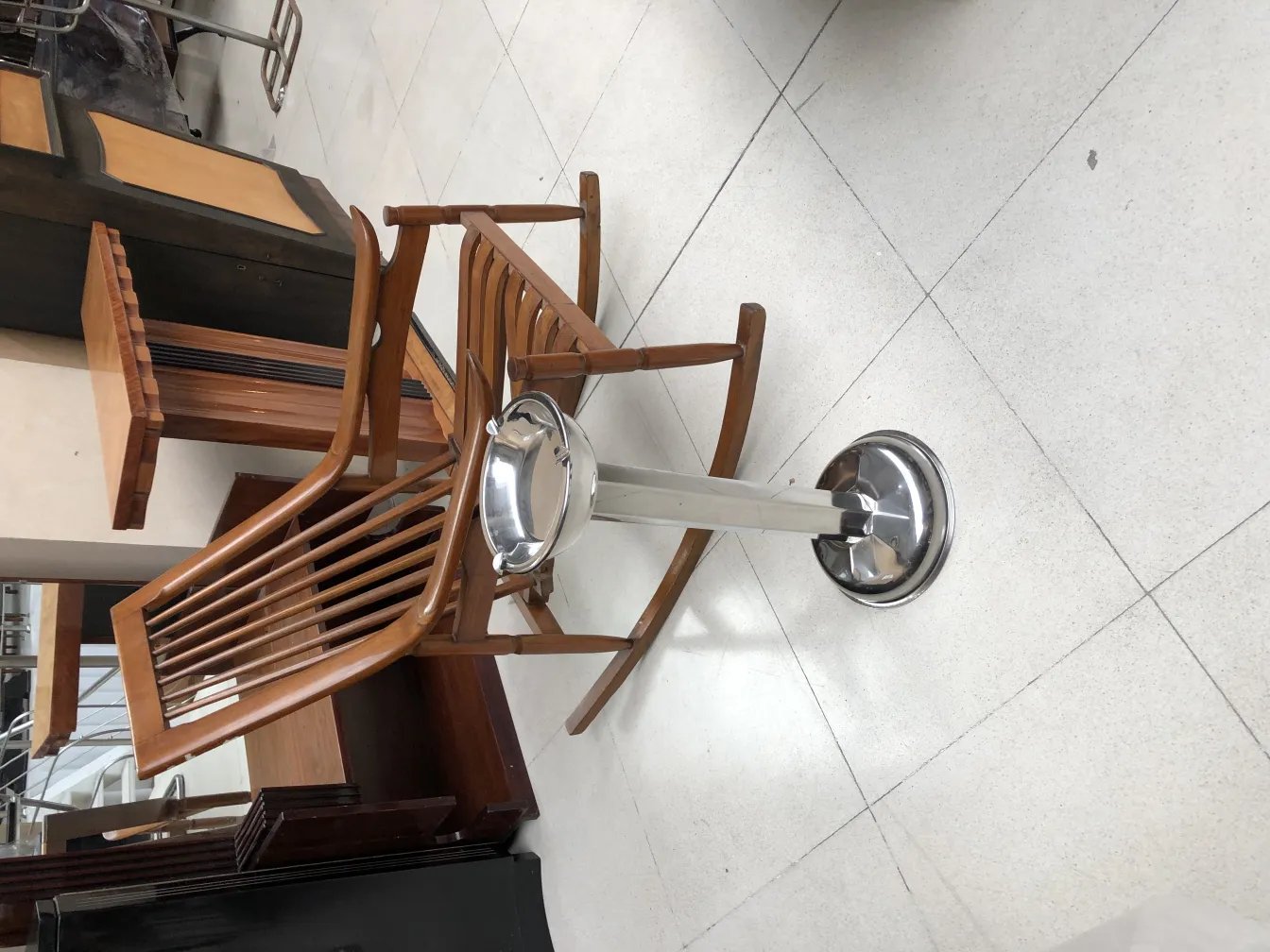 Cendrier sur pied ancien dans un cadre élégant, chaises en bois visibles