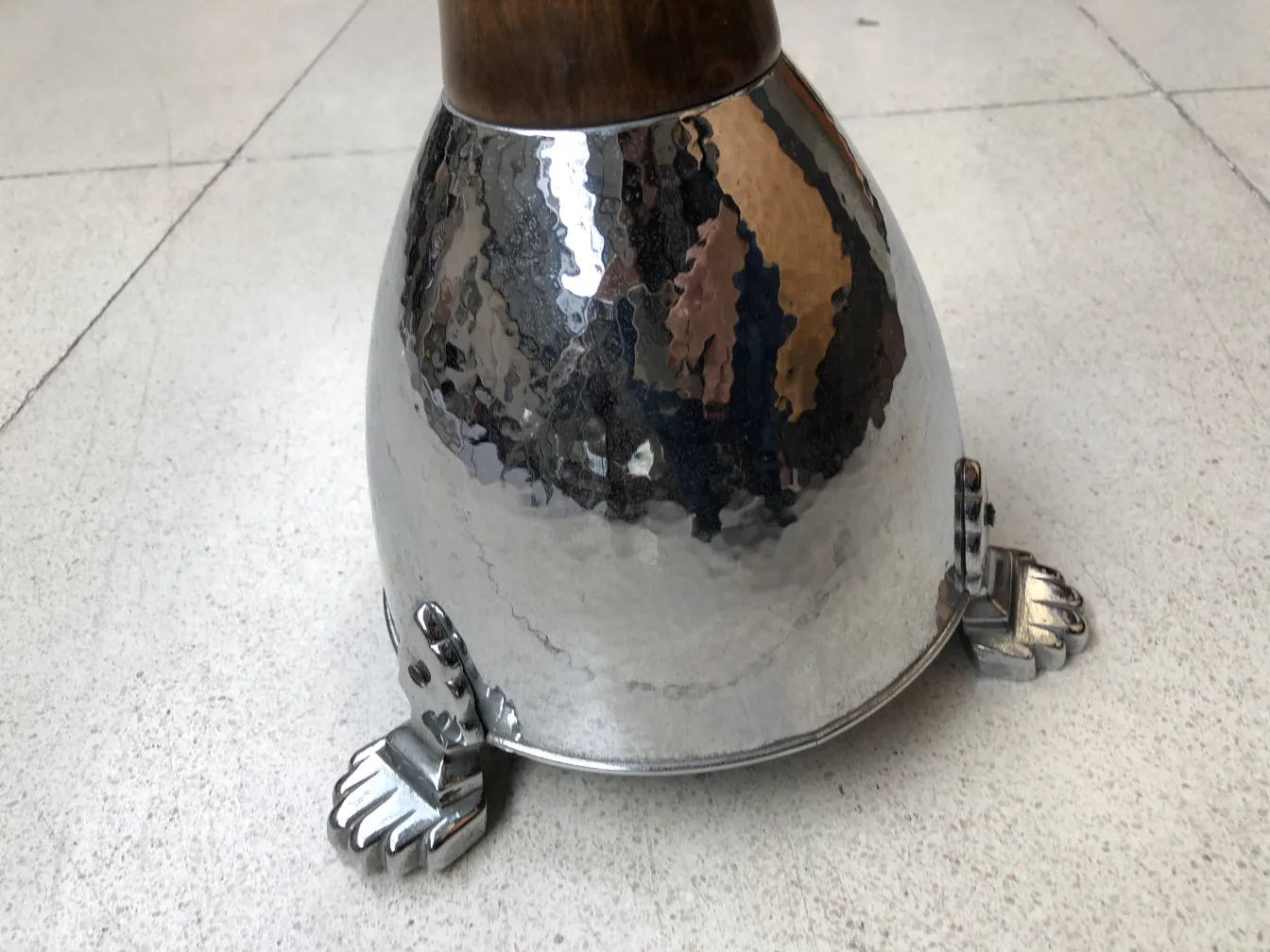 Cinzeiro de pé com base elegante e pés decorativos, ambiente neutro.