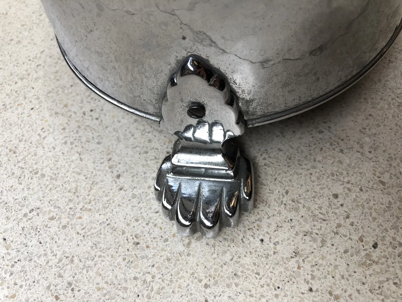 Cinzelo de pé antigo com base decorativa, cenário neutro.