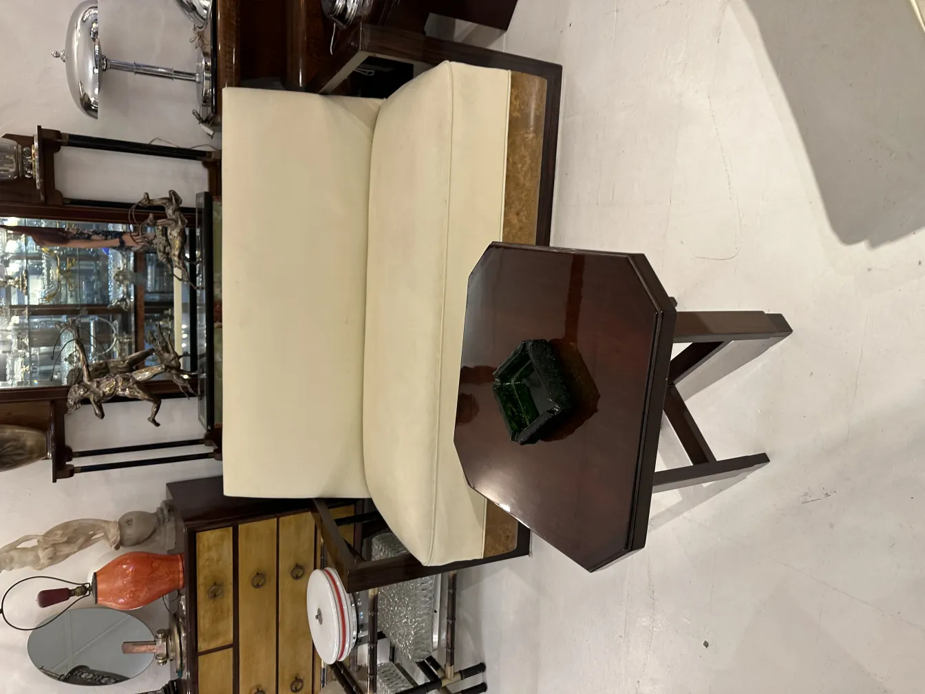 Antique standing ashtray on a wooden table, surrounded by vintage furniture.