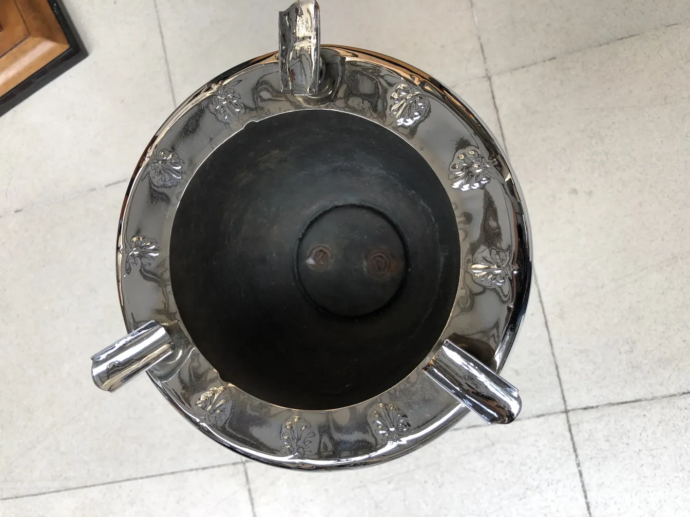 Stehender Aschenbecher mit dekorativen Details und elegantem Design in einer Antiquitätenumgebung.