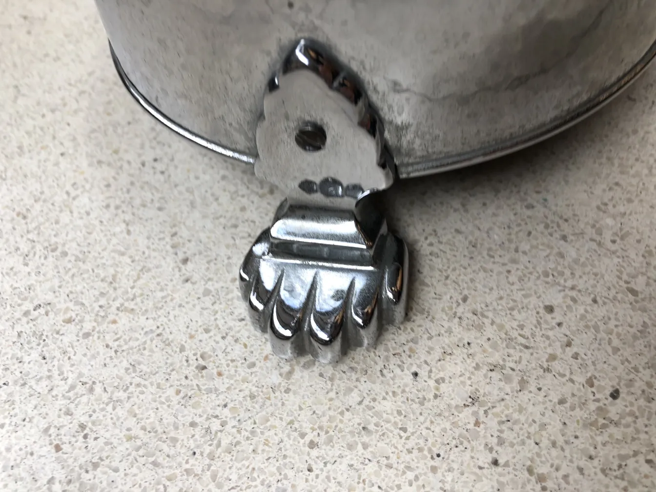 Posacenere in piedi antico con base decorativa in un ambiente neutro.