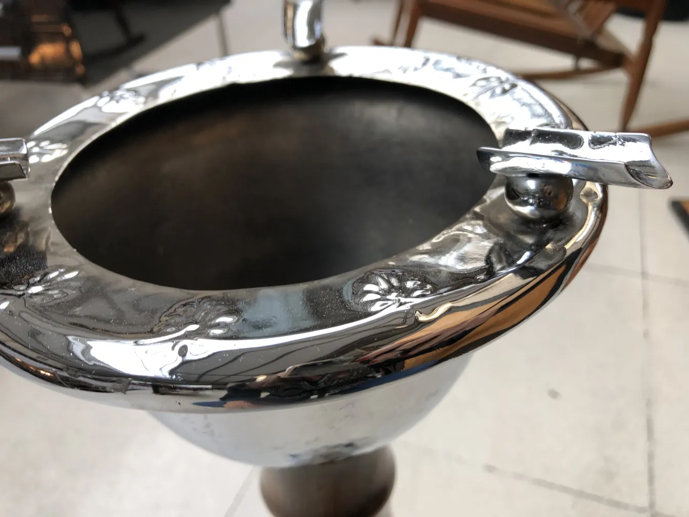 Antique standing ashtray with shiny decorative details and elegant design, set in a cozy environment