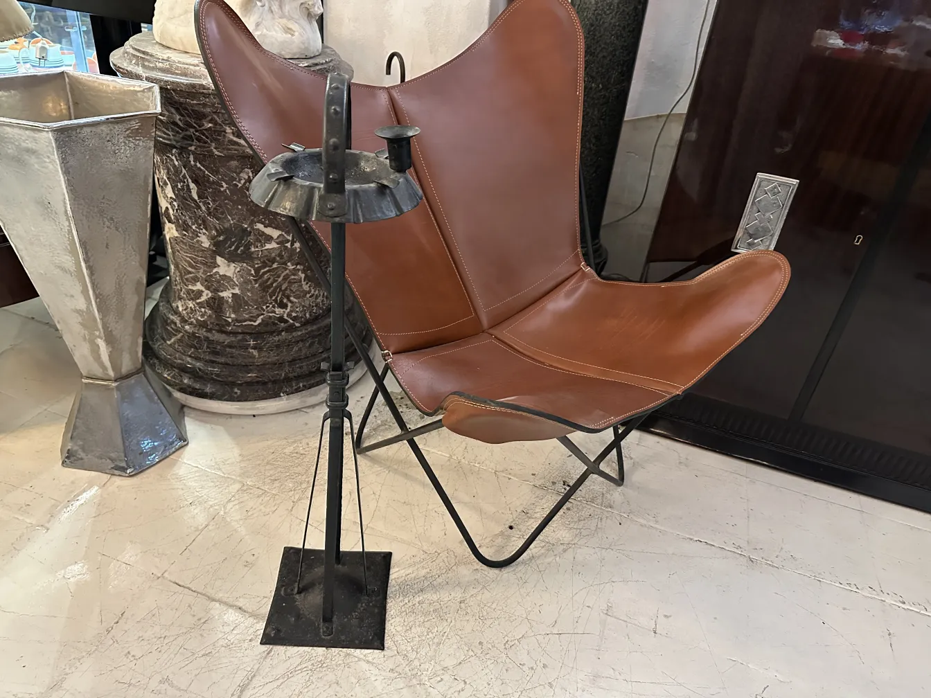 Cendrier sur pied ancien à côté d'une chaise en cuir marron