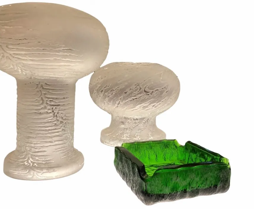 Posacenere in piedi di forma ovale di colore bianco, con un design testurizzato, accanto a un posacenere quadrato verde, creando un'atmosfera vintage.