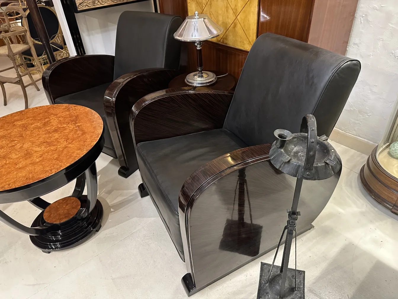 Cinzeiro de pé antigo em um ambiente decorativo com cadeiras e lâmpada.