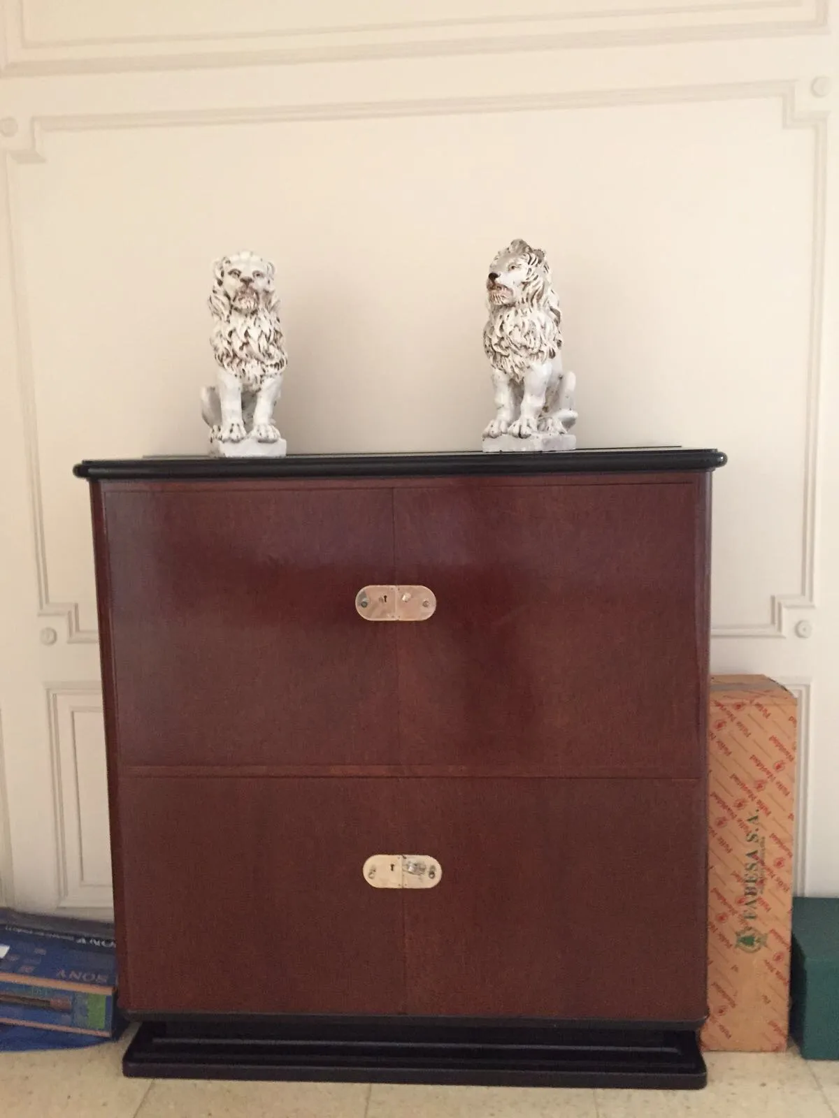Antique bookcase with two decorative lions on top and light background.