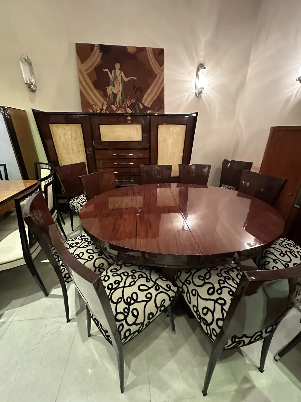 पुरानी अलमारी, चमकदार फिनिश और क्लासिक डिजाइन के साथ, आधुनिक कुर्सियों से घिरी हुई।