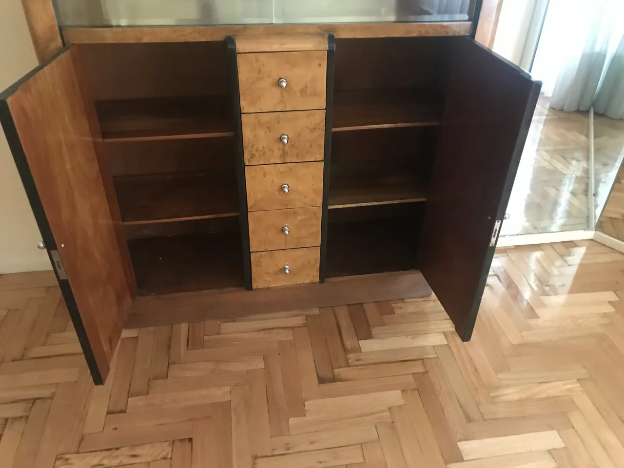 Antique bookcase with open shelves and drawers, light wood.