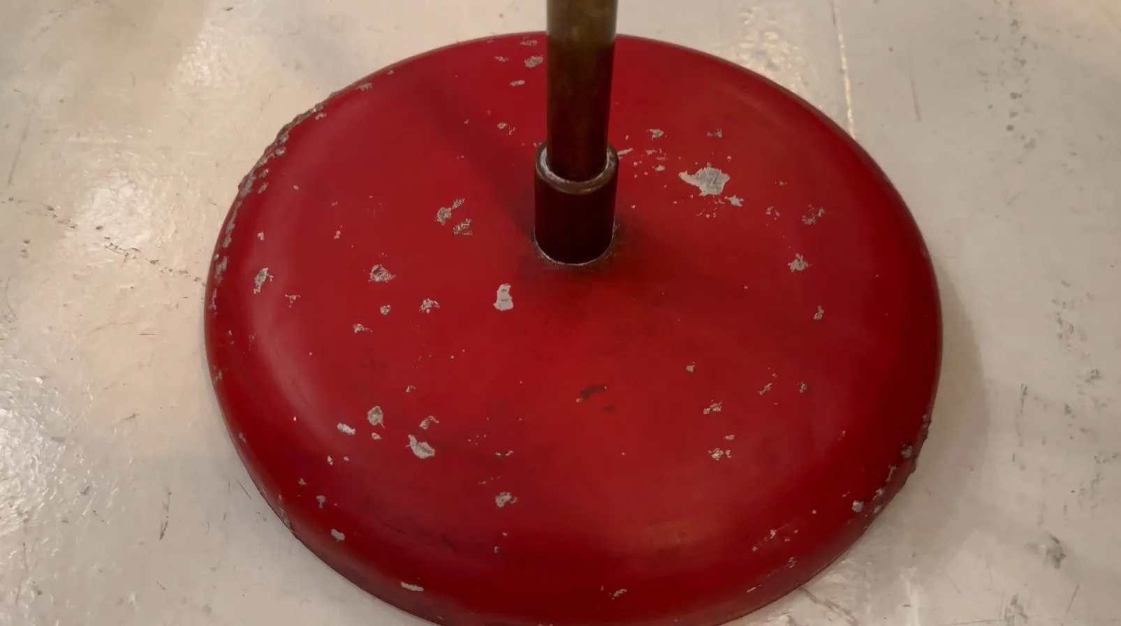 Antique floor lamp with a red base and worn design, perfect for decoration.