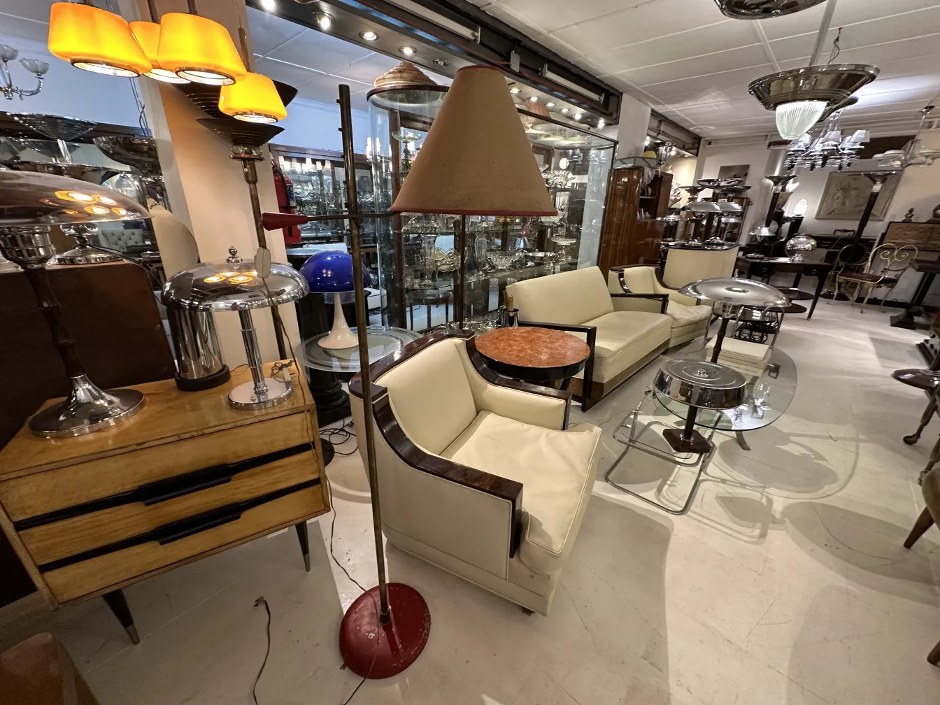 Torchiere ancienne dans un salon élégant avec des fauteuils clairs et une table basse.