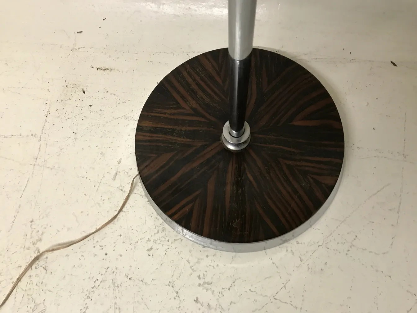 Alte Stehleuchte mit dekorativem Fuß und sichtbarem Kabel.