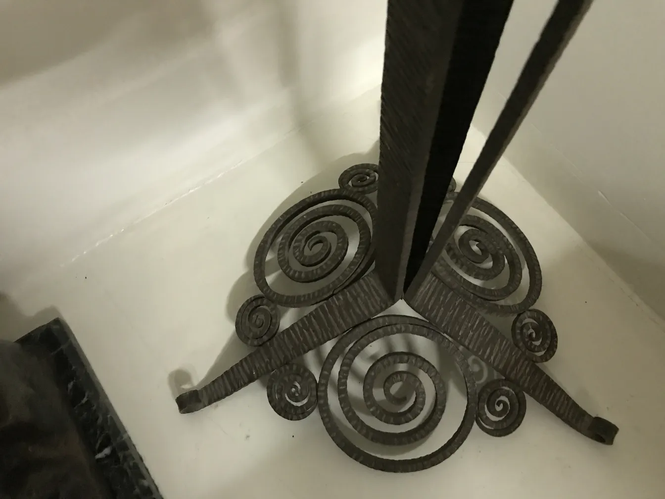 Lampe de sol ancienne avec bases enroulées dans un cadre intérieur léger.