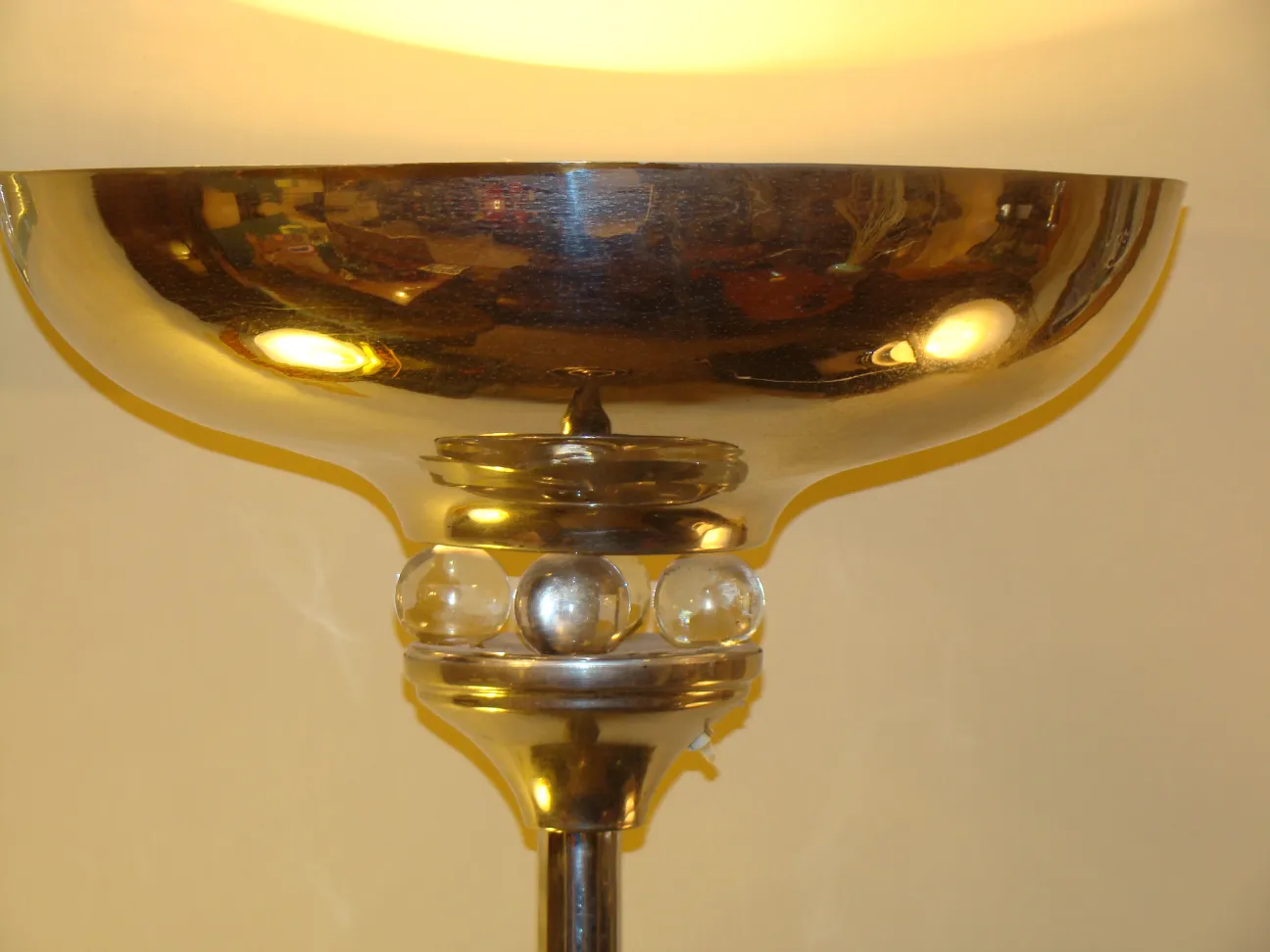 Luminária de pé antiga com detalhes brilhantes e cúpula luminosa em um ambiente acolhedor.