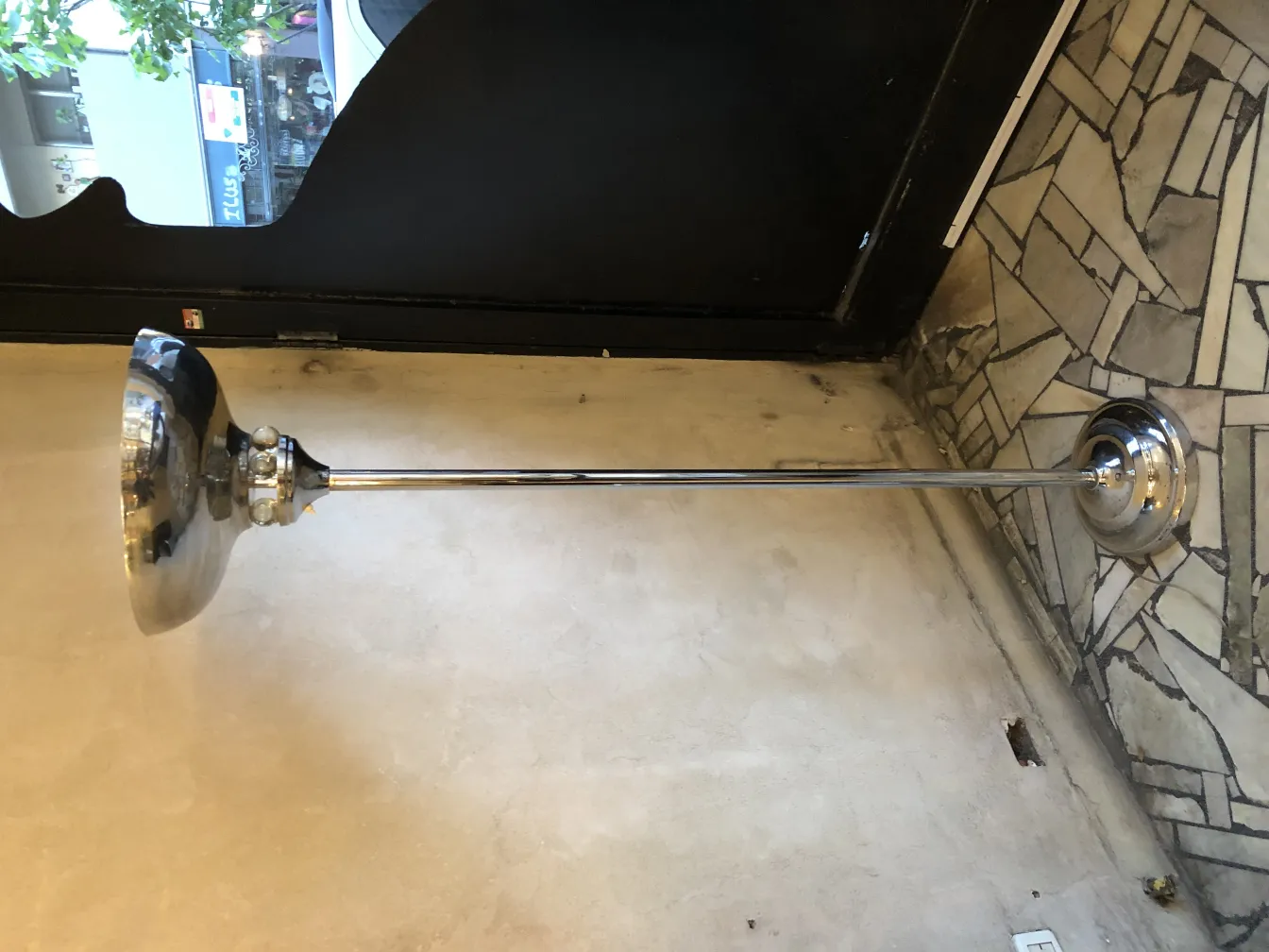 Antique floor lamp with a shiny base and elegant shade in a room with decorative flooring.