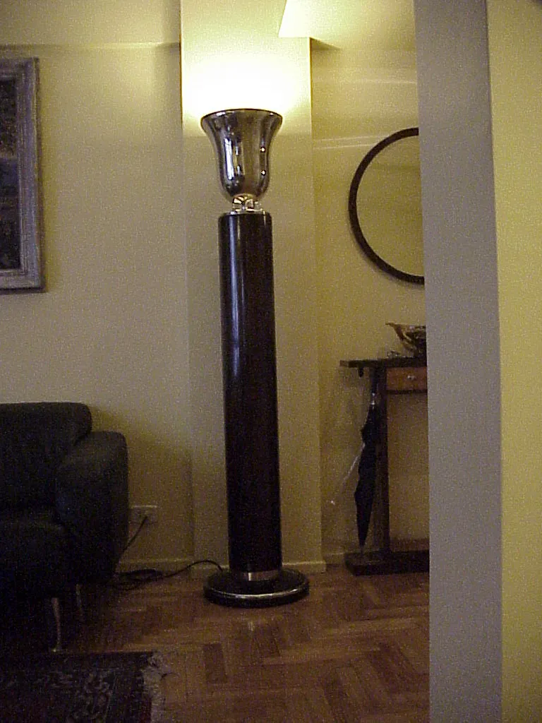 Torchiere ancienne avec base élégante et lumière douce dans une atmosphère chaleureuse.