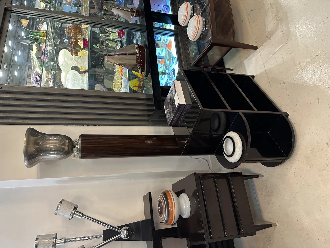 Lámpara de pie antigua con diseño elegante y base sólida, rodeada de otros objetos decorativos.