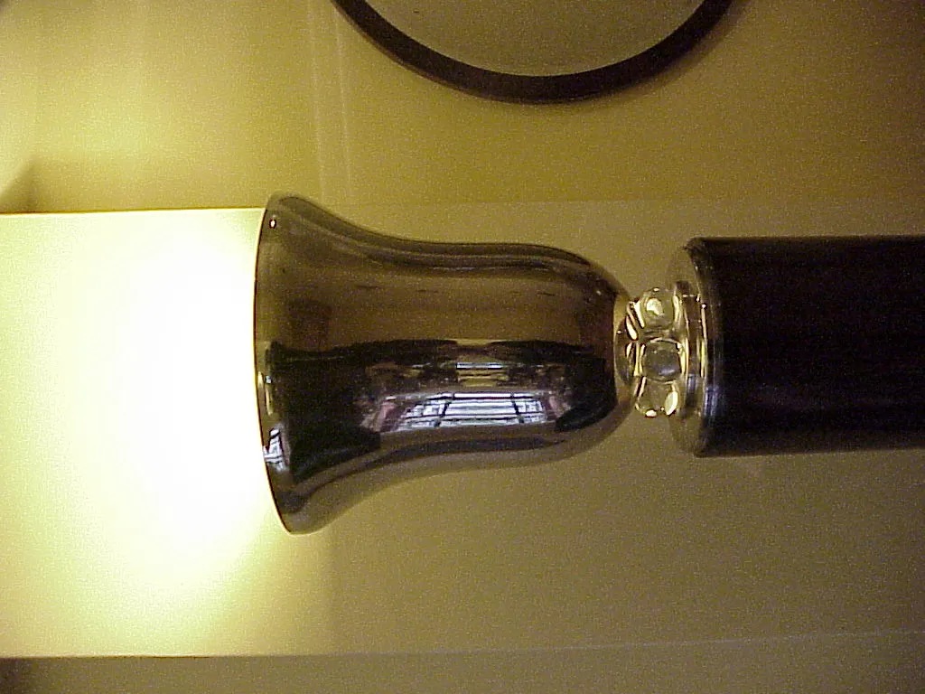 Lampada da terra antica con base lucida e luce soffusa in un ambiente accogliente.