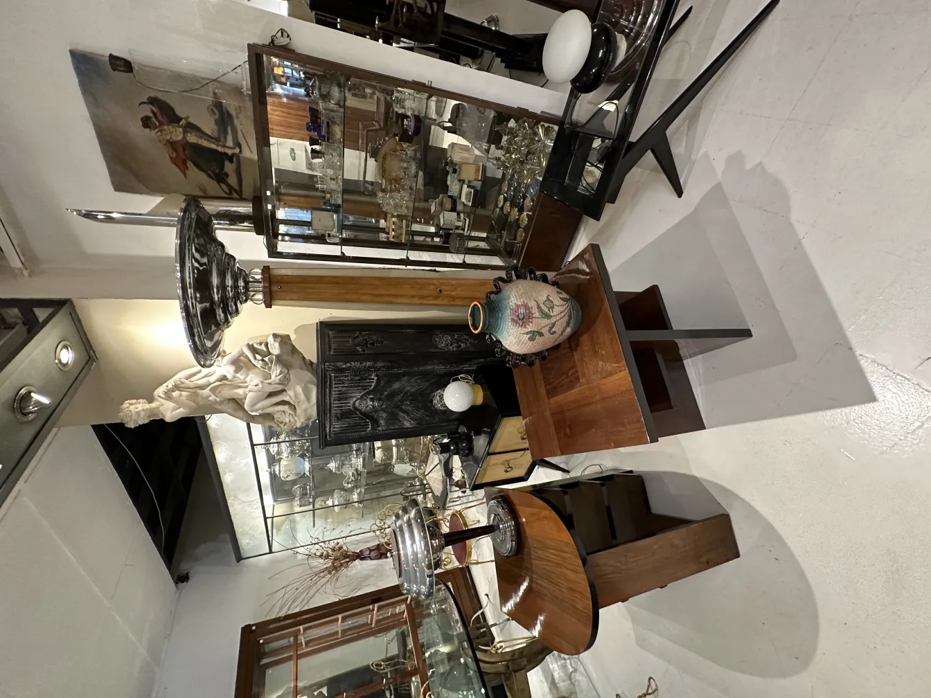 Lampada da terra antica con base elegante e paralume bianco, circondata da decorazioni vintage.