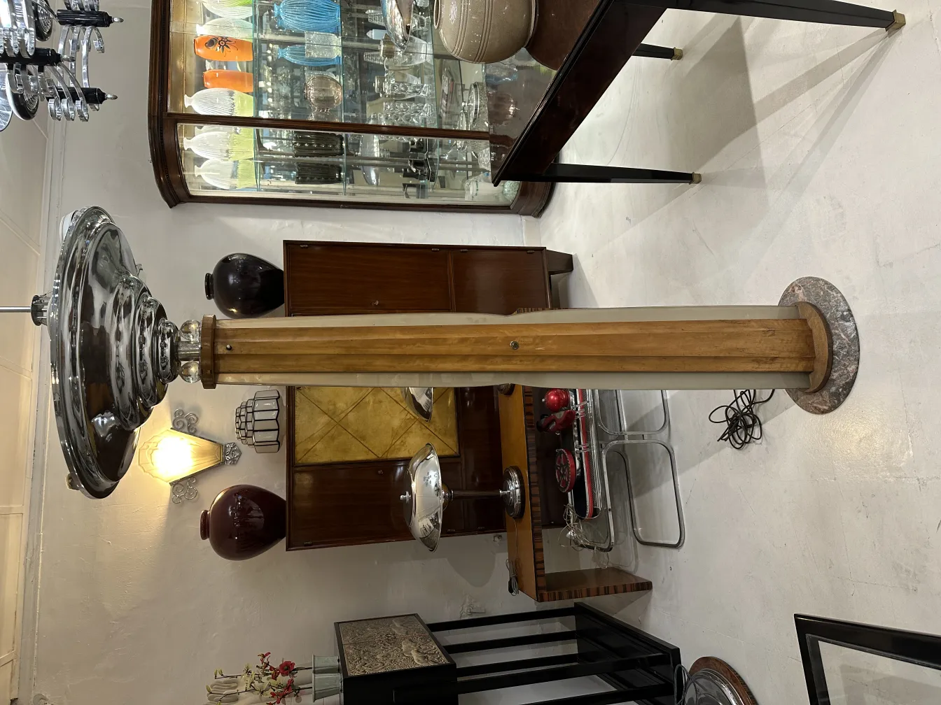 Lampada da terra antica con base elegante e paralume in metallo, circondata da mobili decorativi.