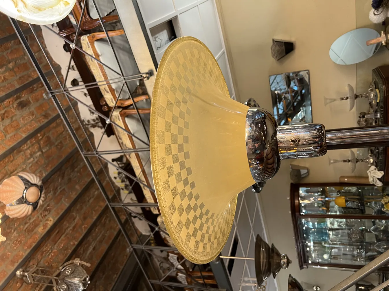 Lampada da terra antica con paralume conico di colore giallo chiaro, circondata da oggetti decorativi vintage.