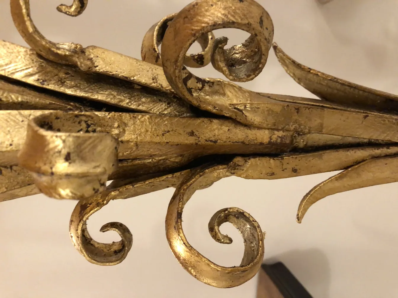 Detalhe de uma antiga luminária de pé com toques dourados e formas elegantes.