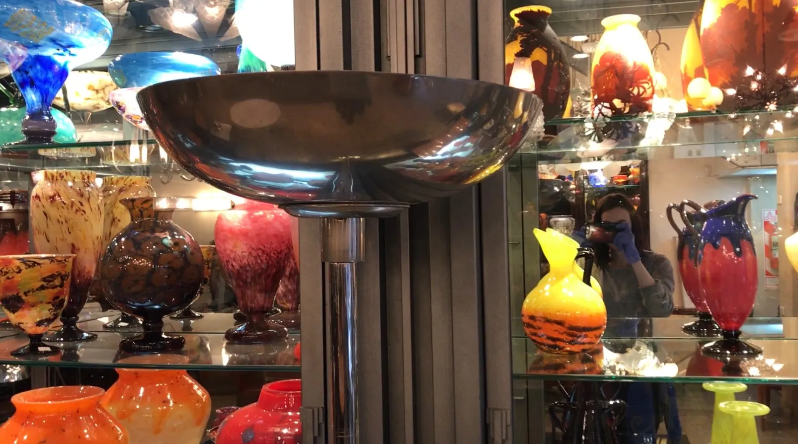 Lampada da terra antica con design elegante davanti a vasi colorati.