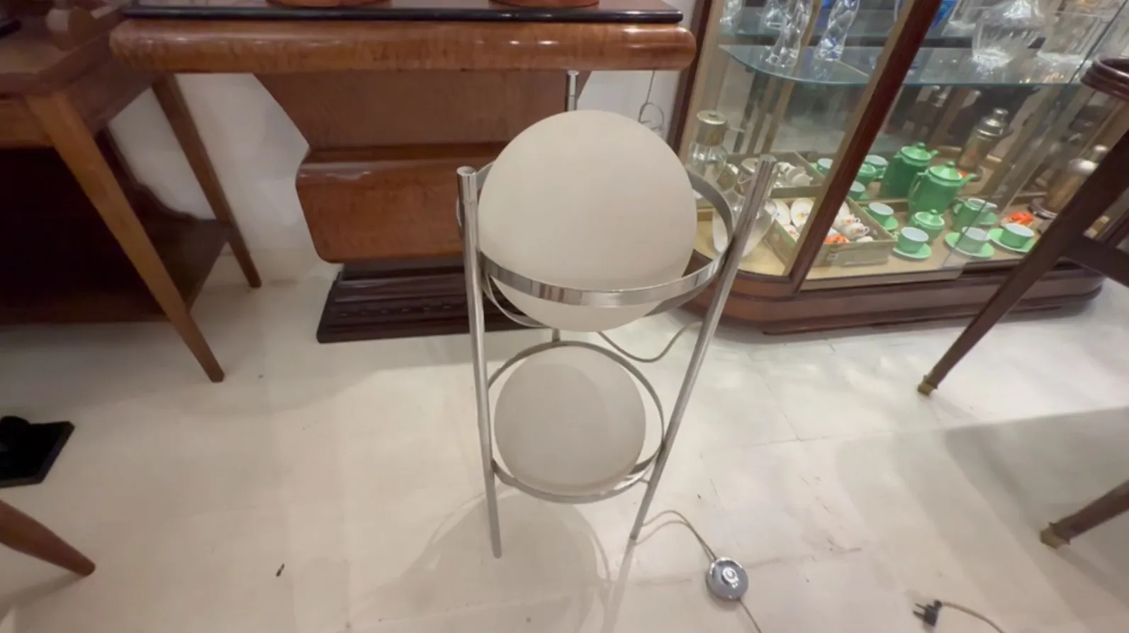 Lámpara de pie antigua con dos esferas decorativas, en un ambiente elegante.