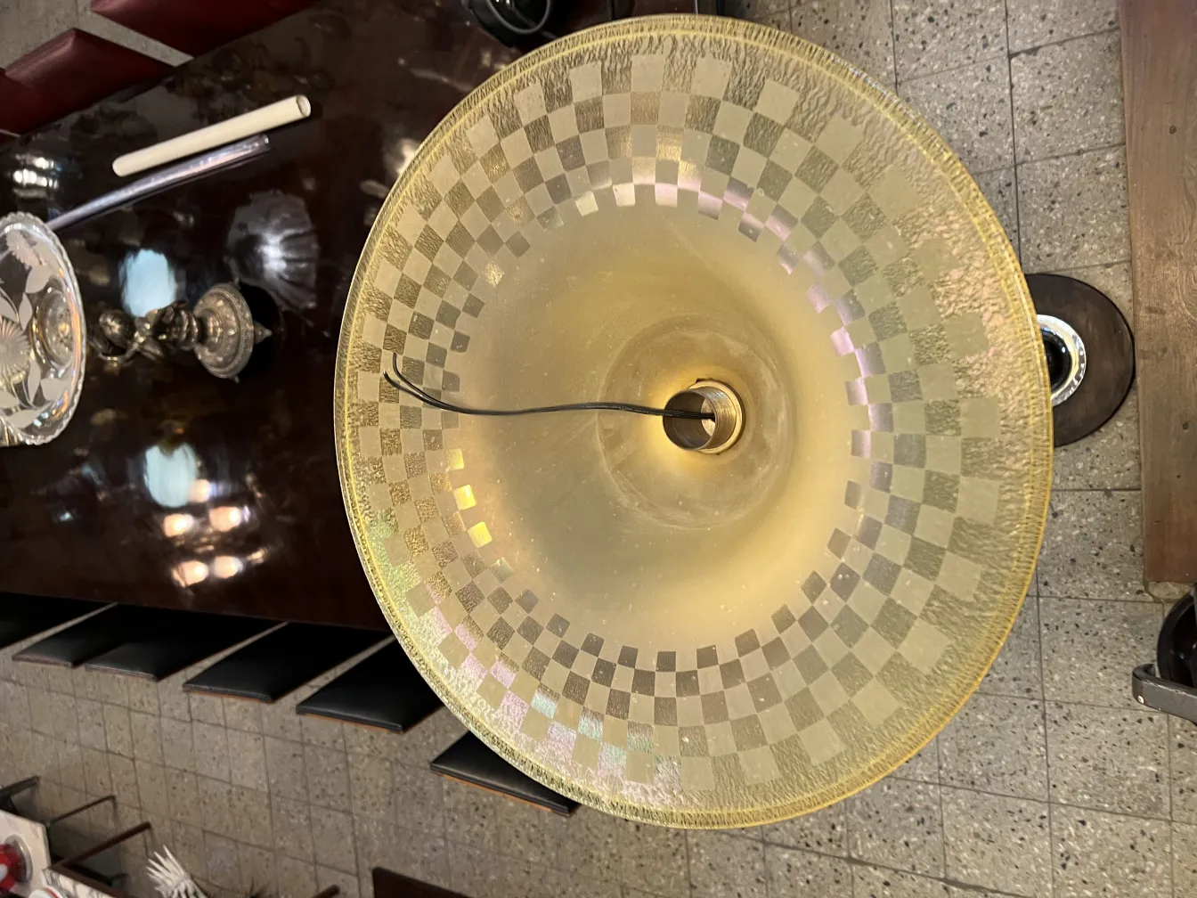 Lampada da terra antica con paralume a motivo geometrico e sfondo chiaro, in un'atmosfera elegante.