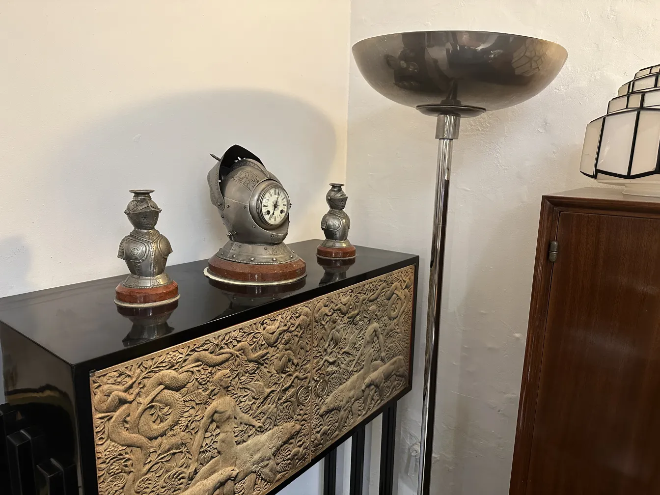 antike stehleuchte im modernen Design auf einem Möbelstück mit reliefierter Oberfläche, daneben silberne Tischlampen